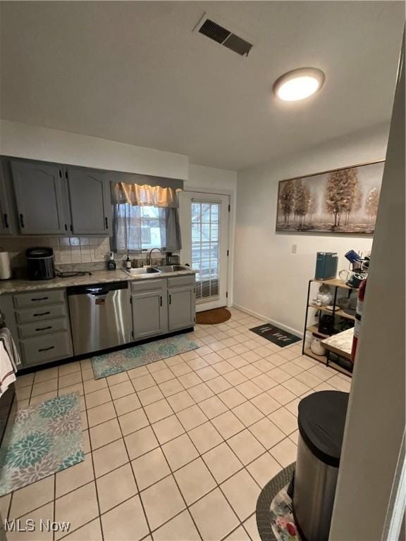 kitchen with sink, light tile patterned floors, gray cabinets, and stainless steel dishwasher