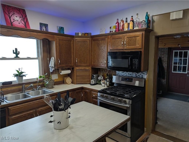 kitchen with stainless steel range with gas cooktop, dark tile patterned flooring, and sink