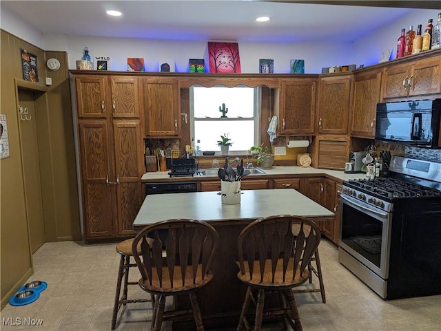 kitchen with a kitchen bar, sink, gas stove, and a center island