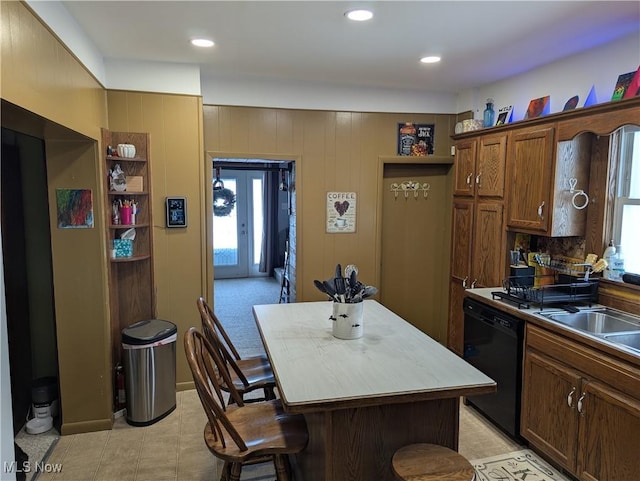 kitchen featuring sink, wood walls, a center island, a kitchen breakfast bar, and dishwasher