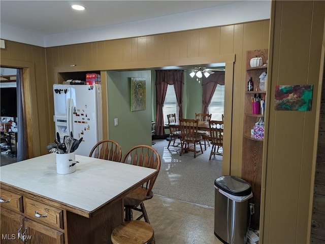 kitchen with white refrigerator with ice dispenser, a center island, and wooden walls