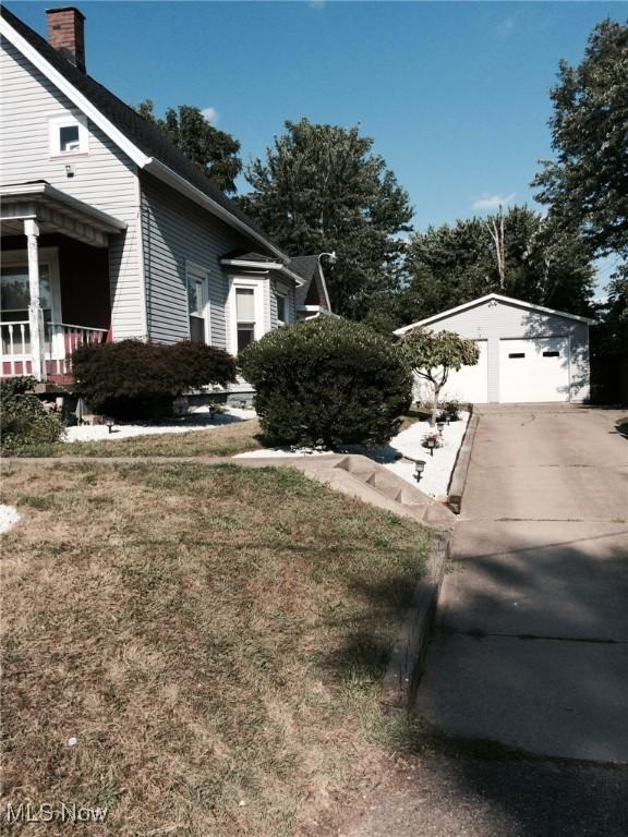 view of home's exterior with covered porch, a garage, an outdoor structure, and a lawn