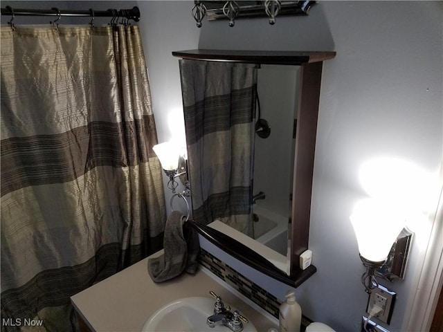 bathroom with shower / bathtub combination with curtain and sink