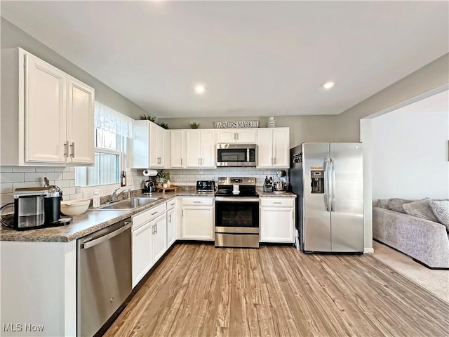 kitchen with sink, tasteful backsplash, light hardwood / wood-style flooring, appliances with stainless steel finishes, and white cabinets