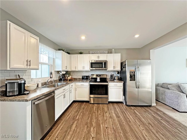 kitchen with sink, white cabinetry, stainless steel appliances, tasteful backsplash, and wood-type flooring