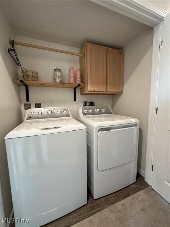 laundry area featuring cabinets, washing machine and clothes dryer, and wood-type flooring