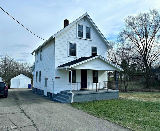 view of front of property with a front yard, covered porch, and a storage shed