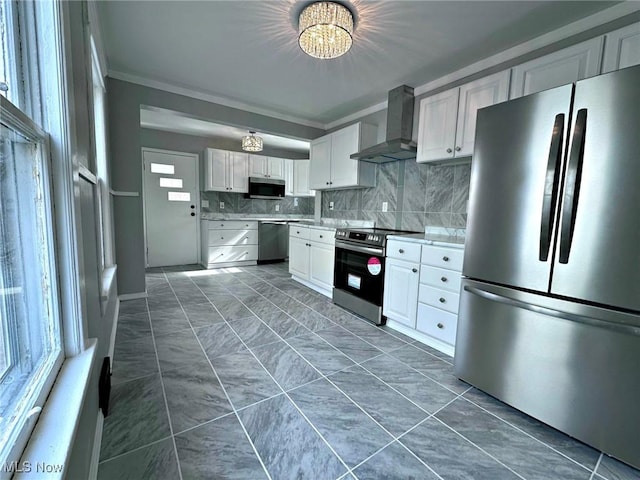 kitchen with appliances with stainless steel finishes, white cabinets, backsplash, ornamental molding, and wall chimney exhaust hood