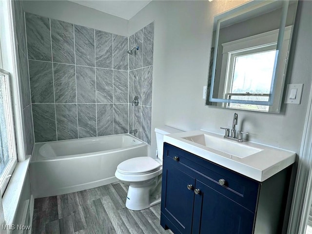 full bathroom with vanity, hardwood / wood-style flooring, tiled shower / bath combo, and toilet