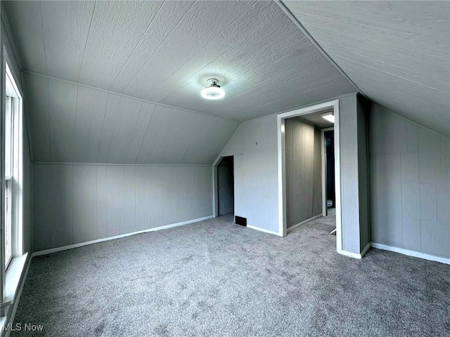 bonus room featuring lofted ceiling, carpet flooring, and a textured ceiling