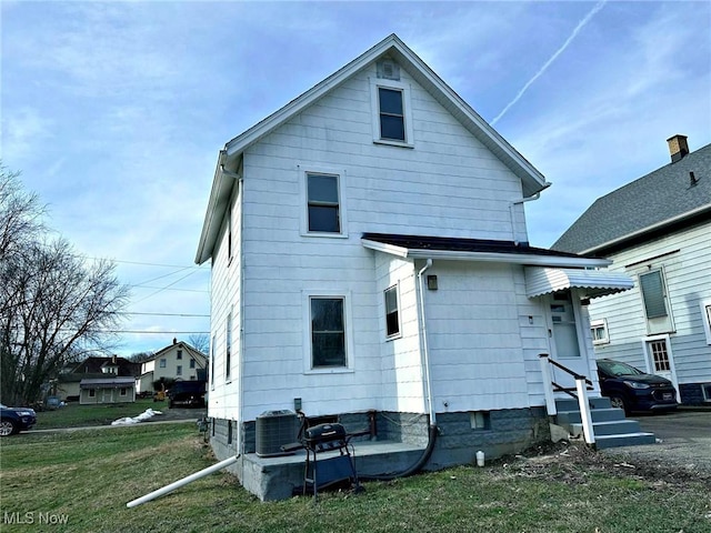 back of property with a yard and central air condition unit