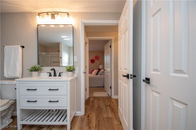 bathroom featuring vanity, toilet, a shower with shower door, and hardwood / wood-style floors