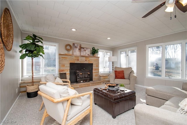 living room with crown molding, light colored carpet, ceiling fan, and a wood stove