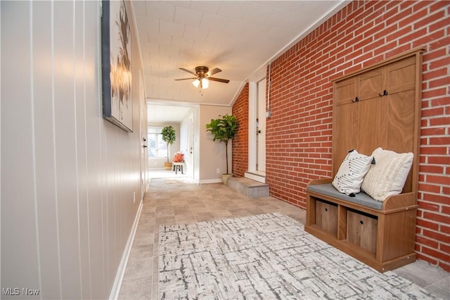 mudroom featuring ceiling fan and brick wall