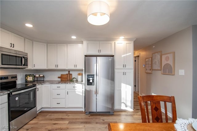 kitchen featuring light stone counters, appliances with stainless steel finishes, light hardwood / wood-style flooring, and white cabinets