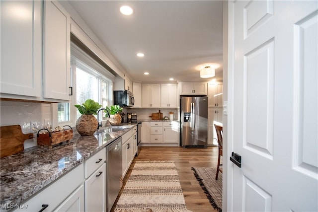 kitchen featuring sink, tasteful backsplash, stainless steel appliances, light hardwood / wood-style floors, and white cabinets