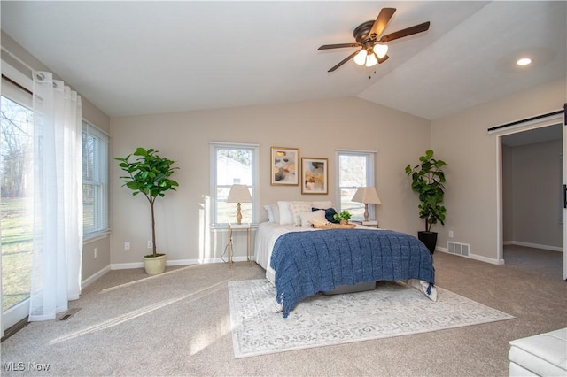 bedroom with ceiling fan, lofted ceiling, a barn door, and carpet