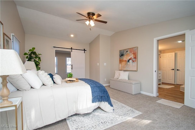 bedroom with vaulted ceiling, light colored carpet, a barn door, and ceiling fan