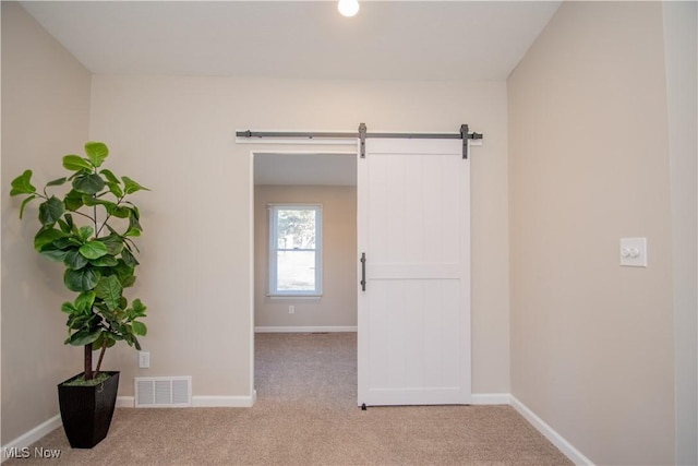 carpeted spare room with a barn door