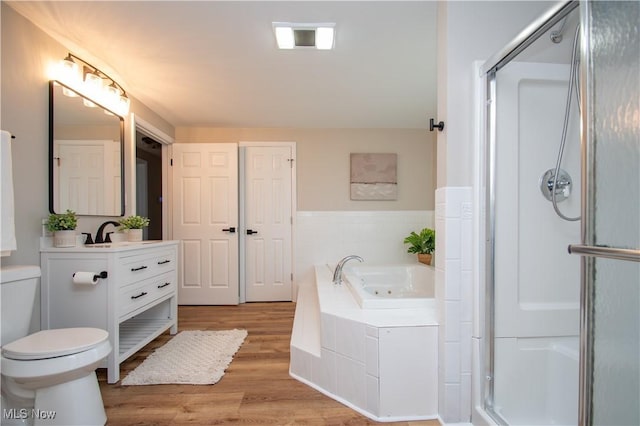 full bathroom featuring toilet, vanity, plus walk in shower, and hardwood / wood-style floors