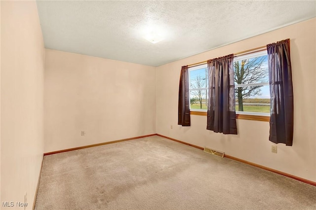 empty room with light carpet and a textured ceiling