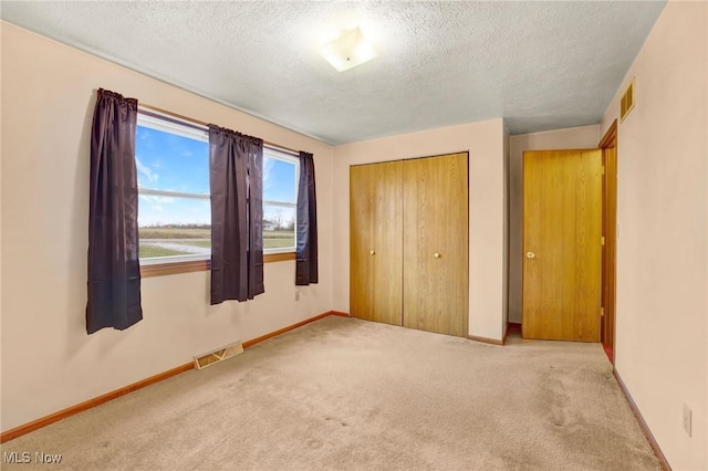 unfurnished bedroom with light colored carpet, a closet, and a textured ceiling