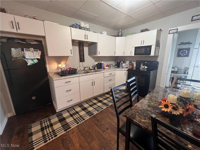 kitchen featuring white cabinetry, dark hardwood / wood-style flooring, light stone counters, and black appliances