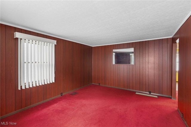 carpeted spare room featuring ornamental molding and wood walls