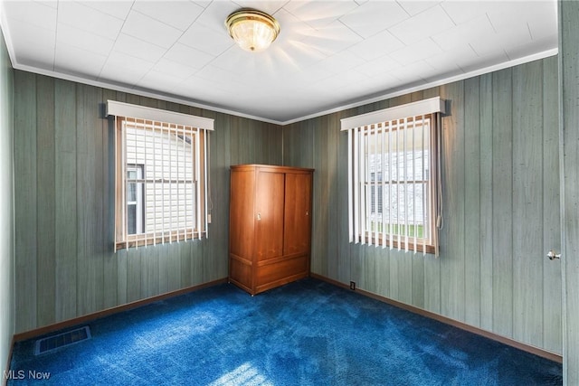 spare room with dark colored carpet and ornamental molding