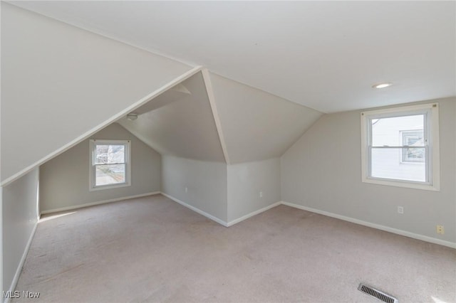 additional living space with vaulted ceiling and light carpet