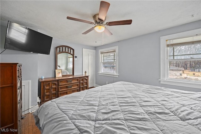 bedroom featuring hardwood / wood-style flooring, ceiling fan, and multiple windows