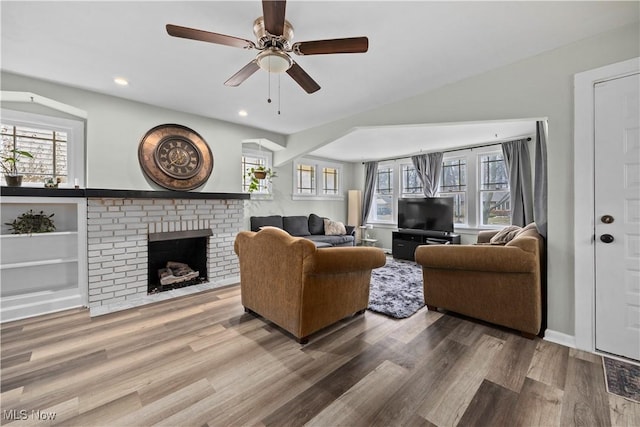 living room featuring a brick fireplace, hardwood / wood-style flooring, and plenty of natural light