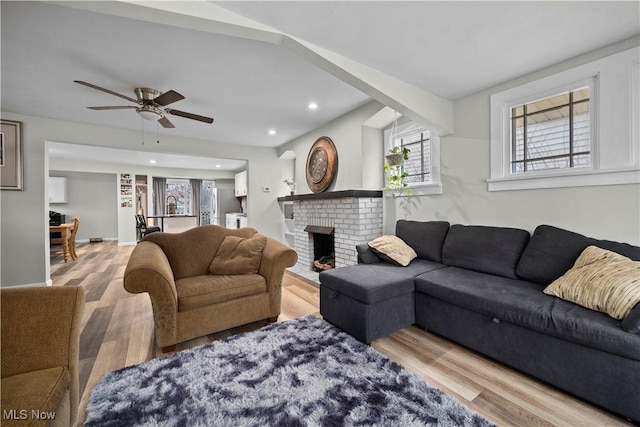 living room with hardwood / wood-style flooring, ceiling fan, and a brick fireplace