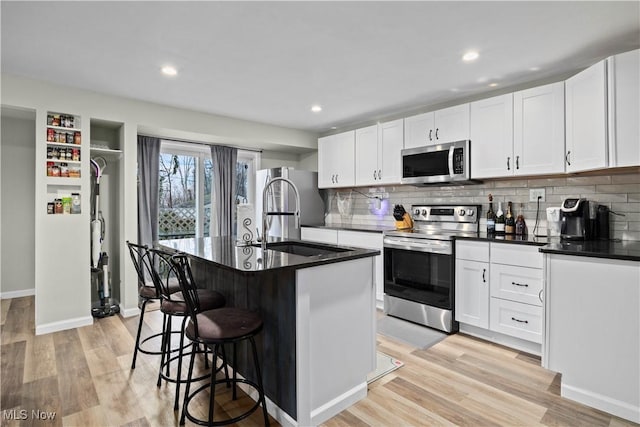 kitchen featuring white cabinetry, stainless steel appliances, sink, and a kitchen island with sink