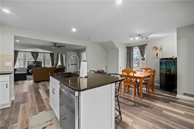 kitchen featuring sink, a kitchen breakfast bar, dishwasher, an island with sink, and white cabinets