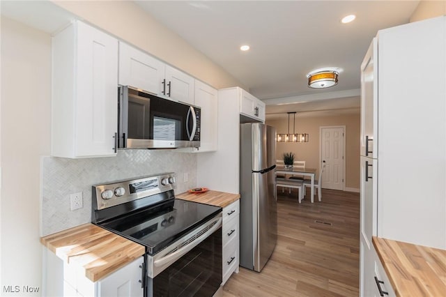 kitchen with appliances with stainless steel finishes, backsplash, white cabinets, and wood counters