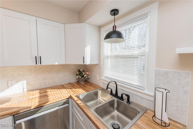 kitchen featuring pendant lighting, sink, dishwasher, butcher block counters, and white cabinets