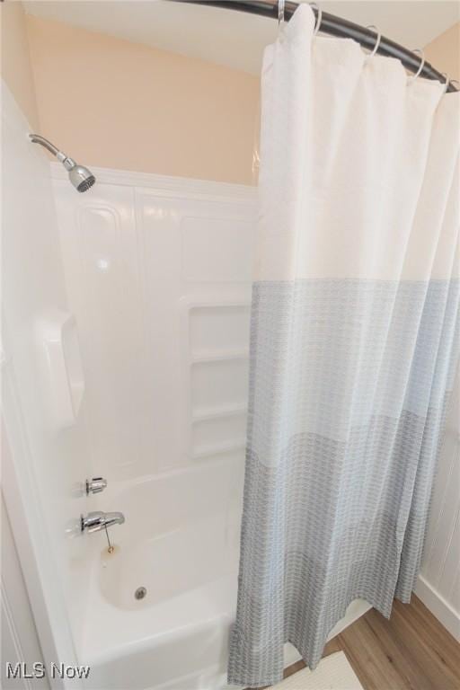 bathroom with shower / bathtub combination with curtain and wood-type flooring