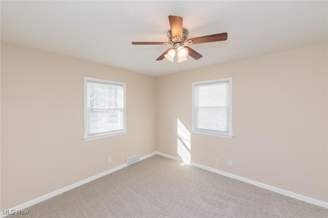 unfurnished room with ceiling fan, light colored carpet, and a healthy amount of sunlight