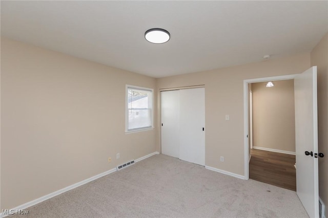 unfurnished bedroom with light colored carpet and a closet