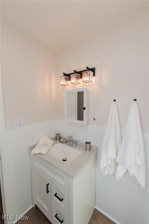 bathroom with hardwood / wood-style flooring, vanity, and tile walls