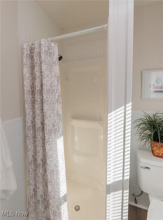 bathroom featuring tile walls, curtained shower, and toilet