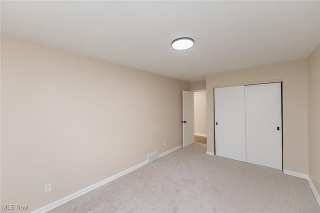 unfurnished bedroom featuring light carpet and a closet