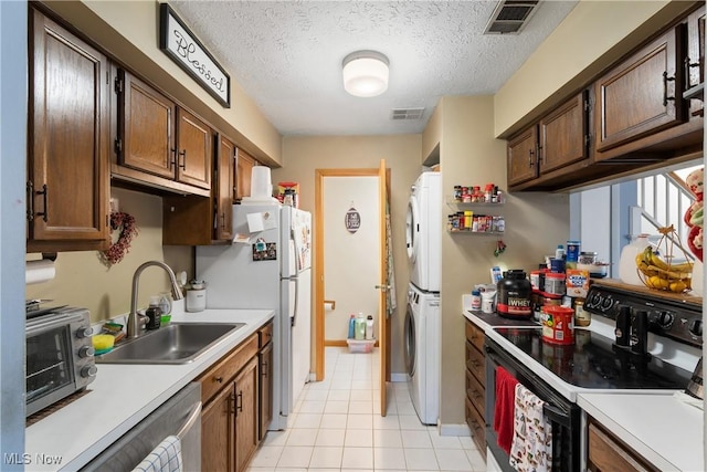 kitchen featuring sink, stacked washer and dryer, white fridge, electric range, and a textured ceiling