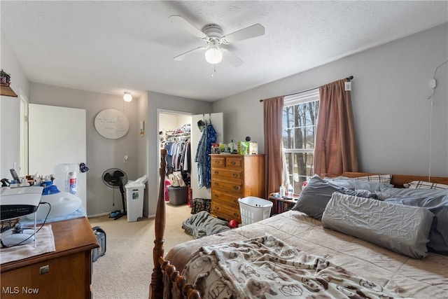 bedroom featuring a spacious closet, light colored carpet, ceiling fan, a textured ceiling, and a closet