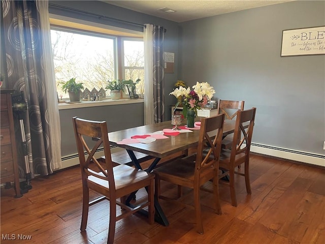 dining room with a baseboard heating unit and dark wood-type flooring