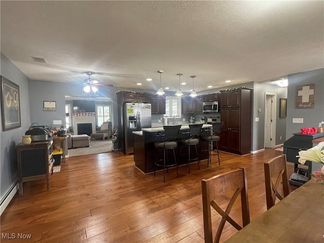 kitchen featuring dark brown cabinetry, a center island, dark hardwood / wood-style floors, a kitchen breakfast bar, and stainless steel appliances