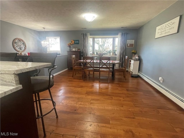 dining area featuring a baseboard heating unit, plenty of natural light, dark hardwood / wood-style floors, and a chandelier