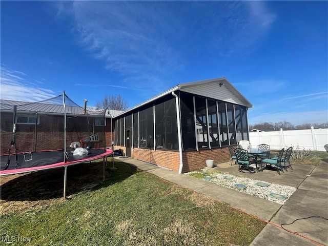 view of side of property with a patio, a sunroom, a yard, and a trampoline