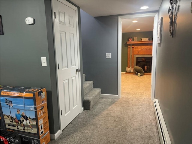 corridor with a baseboard heating unit and carpet